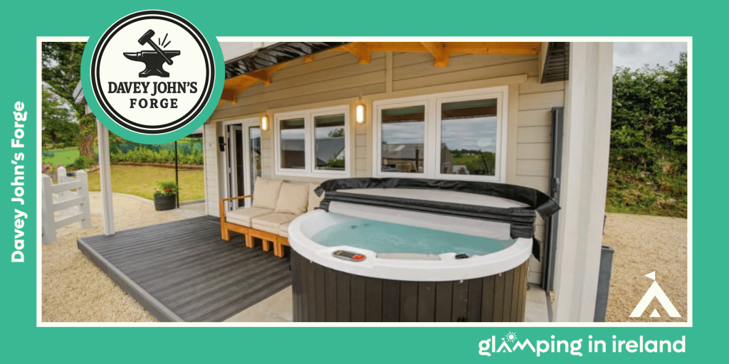 Image is of a luxury log cabin at Davey John’s Forge, a glampsite in County DOnegal, shows a hot tub on a covered porch