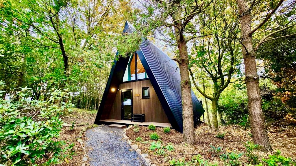 Image is of a luxury wooden lodge, nestled among trees at BallyBurren, Northern Ireland