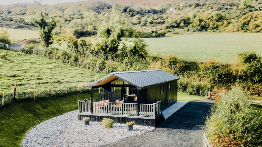 Large cabin with raised deck at Briarfield Farm Stays, a glampsite in Northern Ireland, wit rural and mountain backdrop