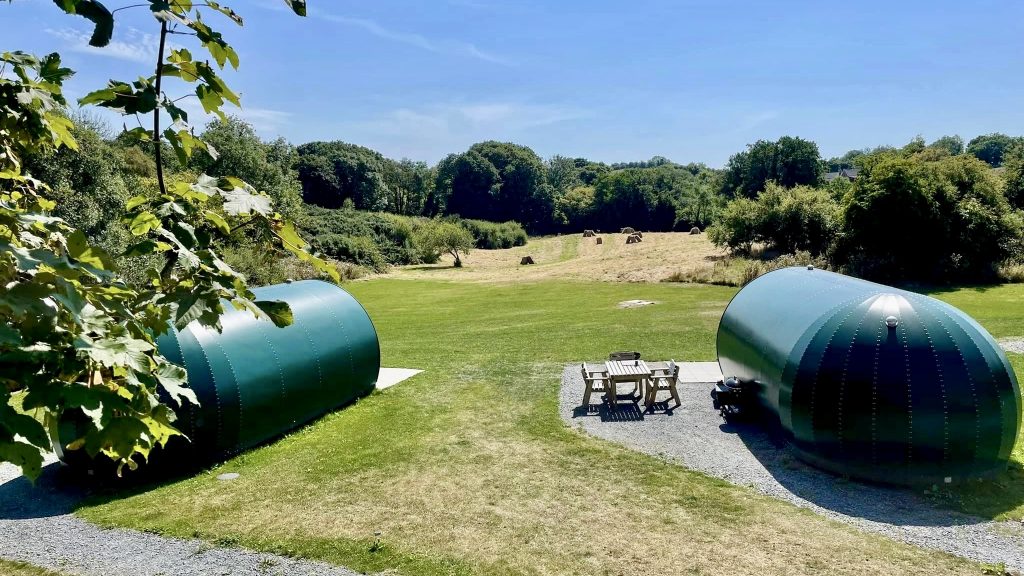Two luxury glamping pods, with picnic benches beside, with a panoramic rural views in County Down, at Kinelarty Pods.